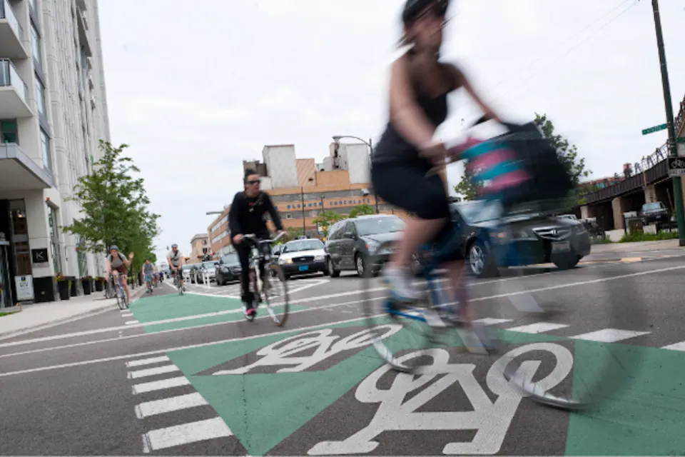 Cyclists riding on green painted bike lane protected by flexible post delineators in Chicago, Illinois.